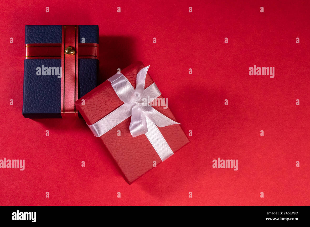 Red and blue gift boxes shot from top, decorated with ribbons on red background with copy space Stock Photo