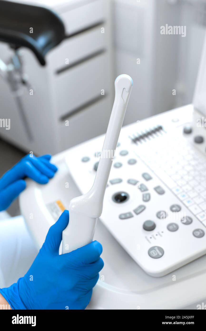 A gynecologist sets up an ultrasound machine. A transvaginal ultrasound