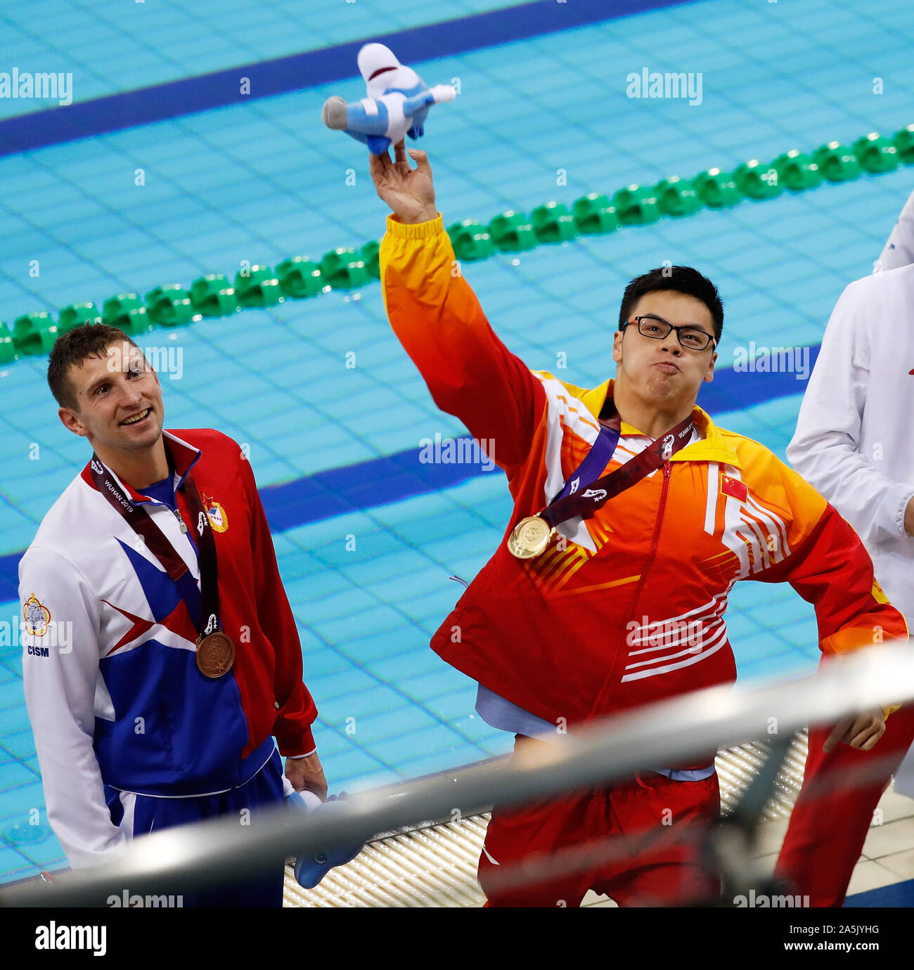 (191021) -- WUHAN, Oct. 21, 2019 (Xinhua) -- Ling Huanan (R) of China throws the mascot to the stands after the awarding ceremony of the men's 100m rescue medley final of lifesaving at the 7th CISM Military World Games in Wuhan, capital of central China's Hubei Province, Oct. 21, 2019. (Xinhua/Wang Lili) Stock Photo