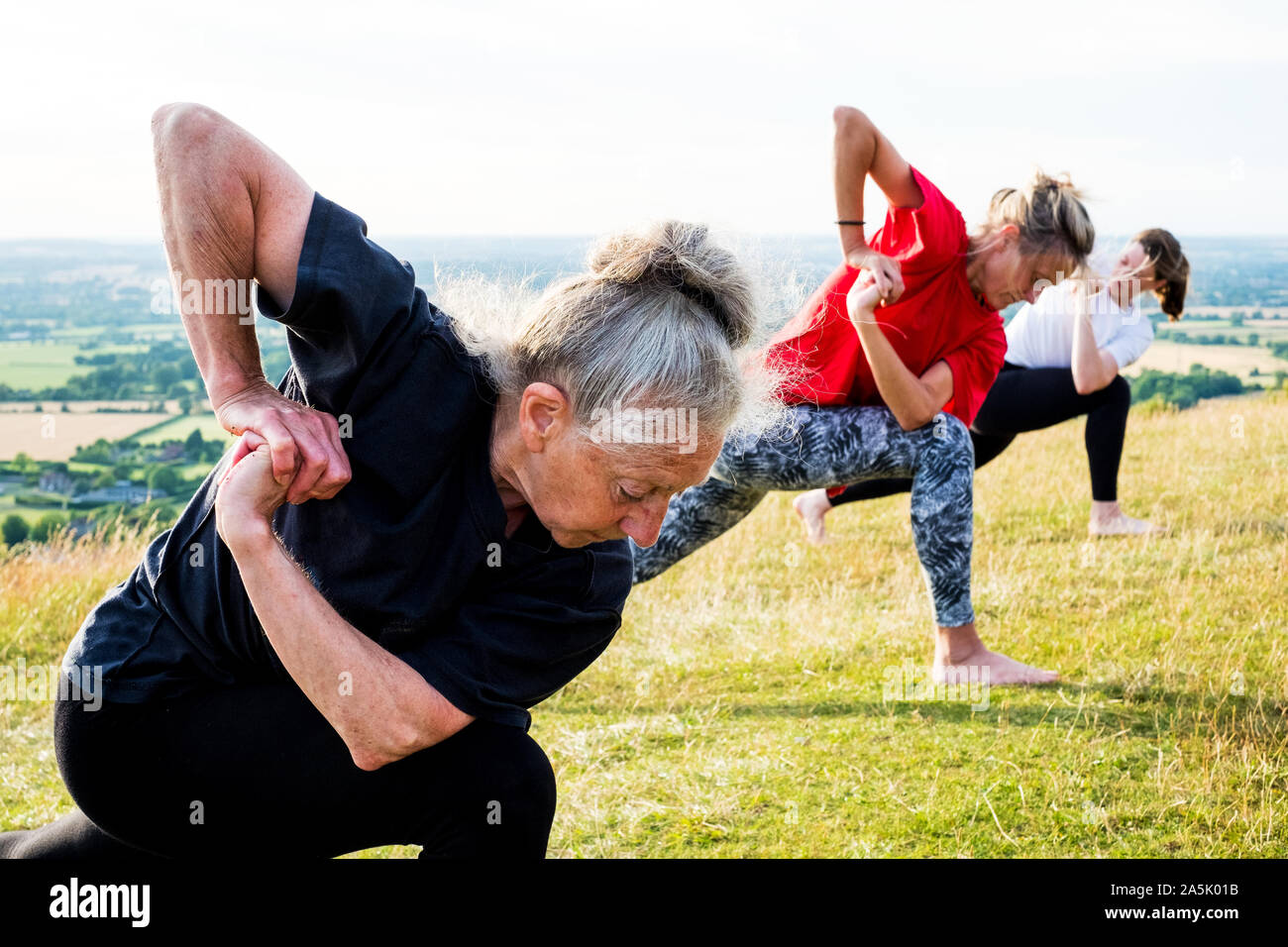 Group of women taking part in a yoga class on a hillside Stock Photo