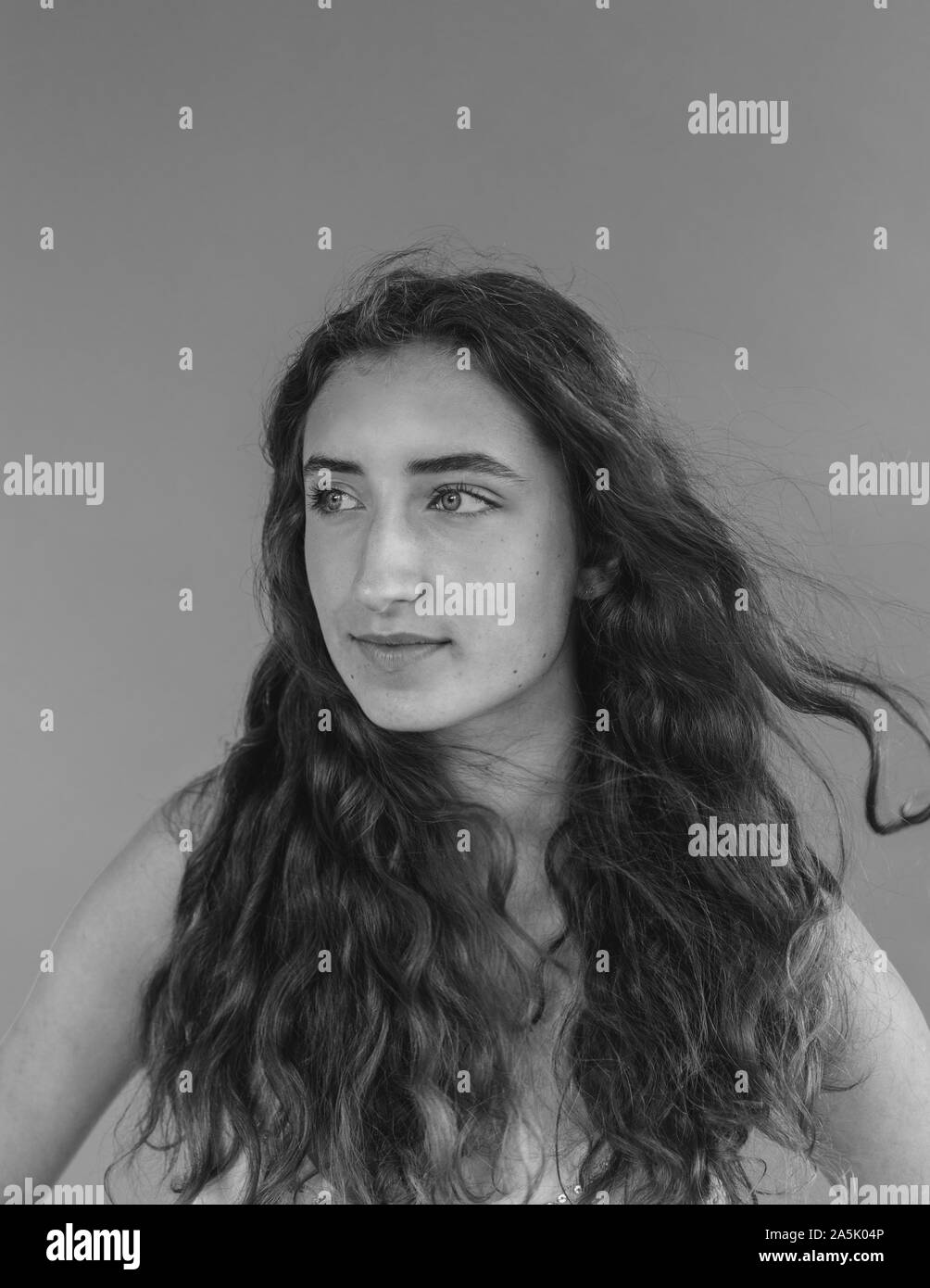 Black and white portrait of pretty sixteen year old girl, wind blowing her long wavy hair Stock Photo