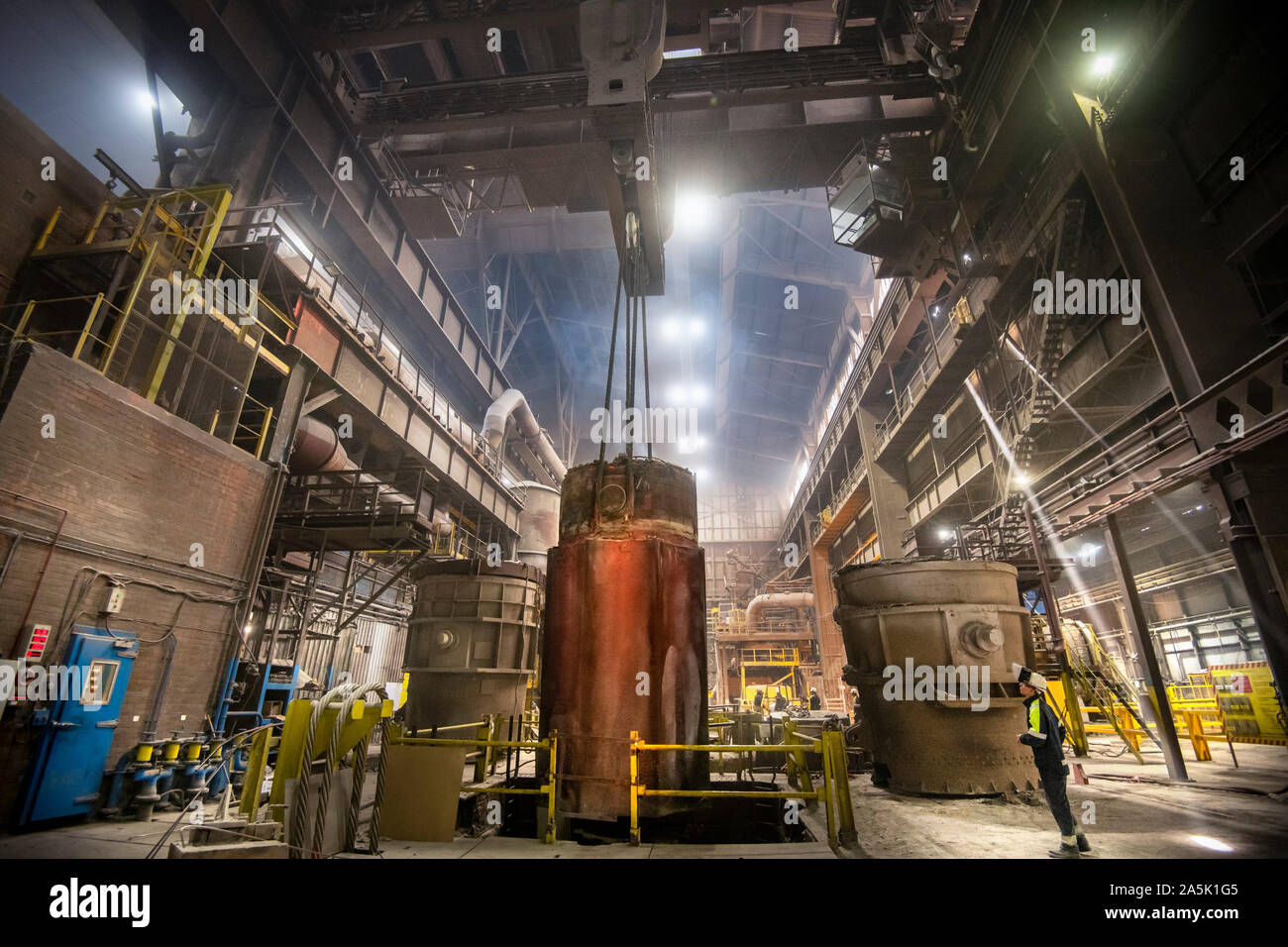 200 ton red hot steel ingot being lifted from mould in steelworks Stock Photo