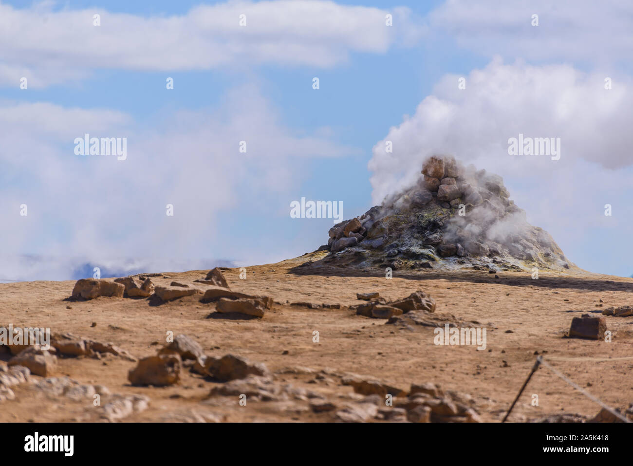 Hillside landscape with rock formation and rising steam against blue sky, Akureyri, Eyjafjardarsysla, Iceland Stock Photo