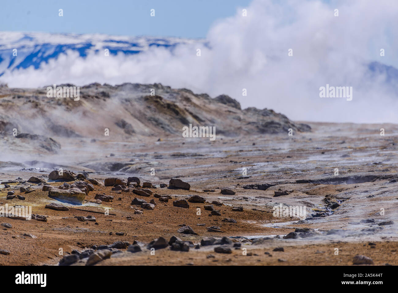 Barren landscape with steam rising beyond rocks, Akureyri, Eyjafjardarsysla, Iceland Stock Photo