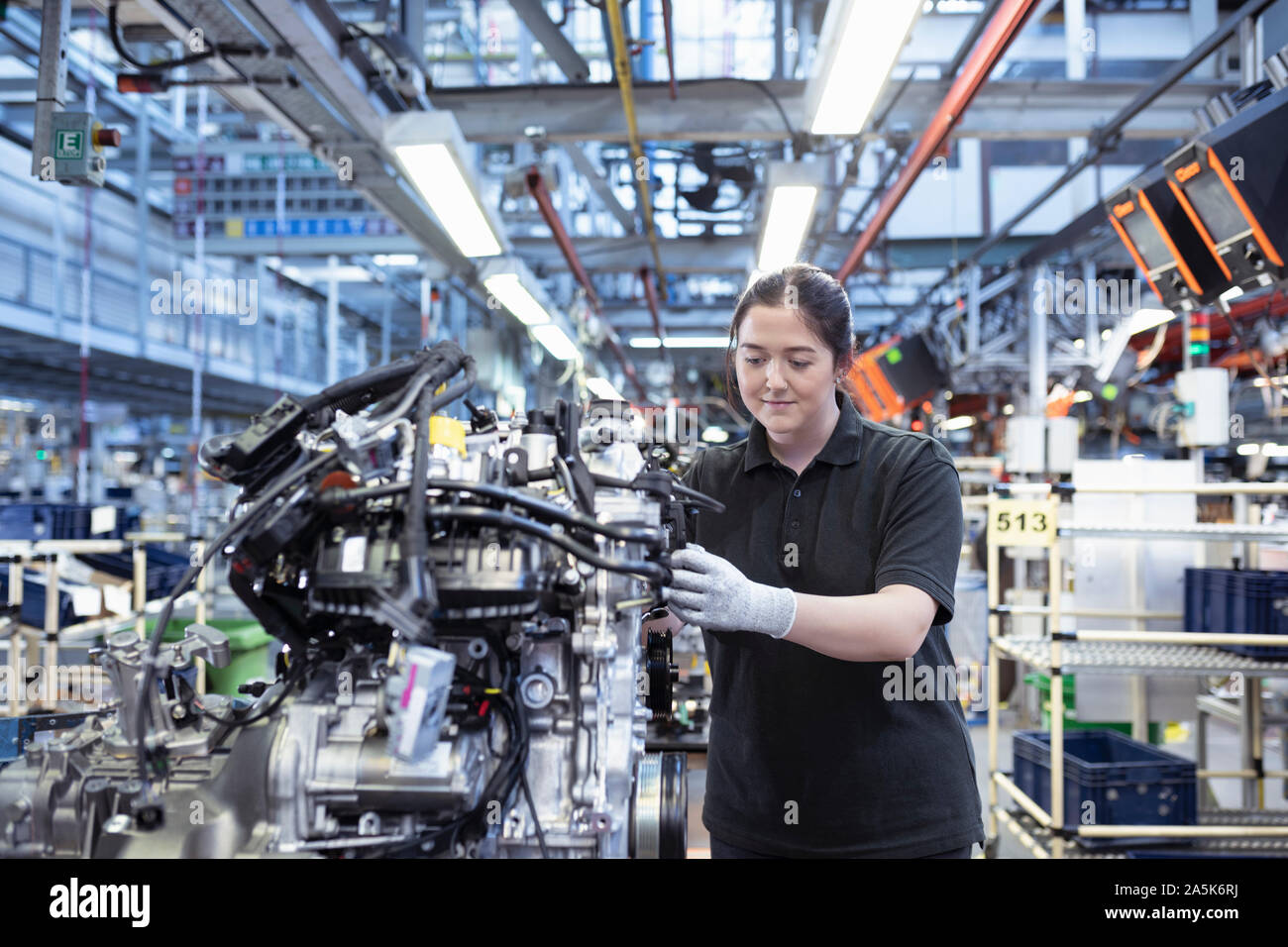 Female apprentice working on engine assembly line in car factory Stock Photo