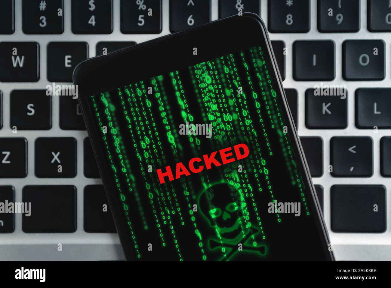 Closeup of hacked smartphone lying on laptop keyboard Stock Photo