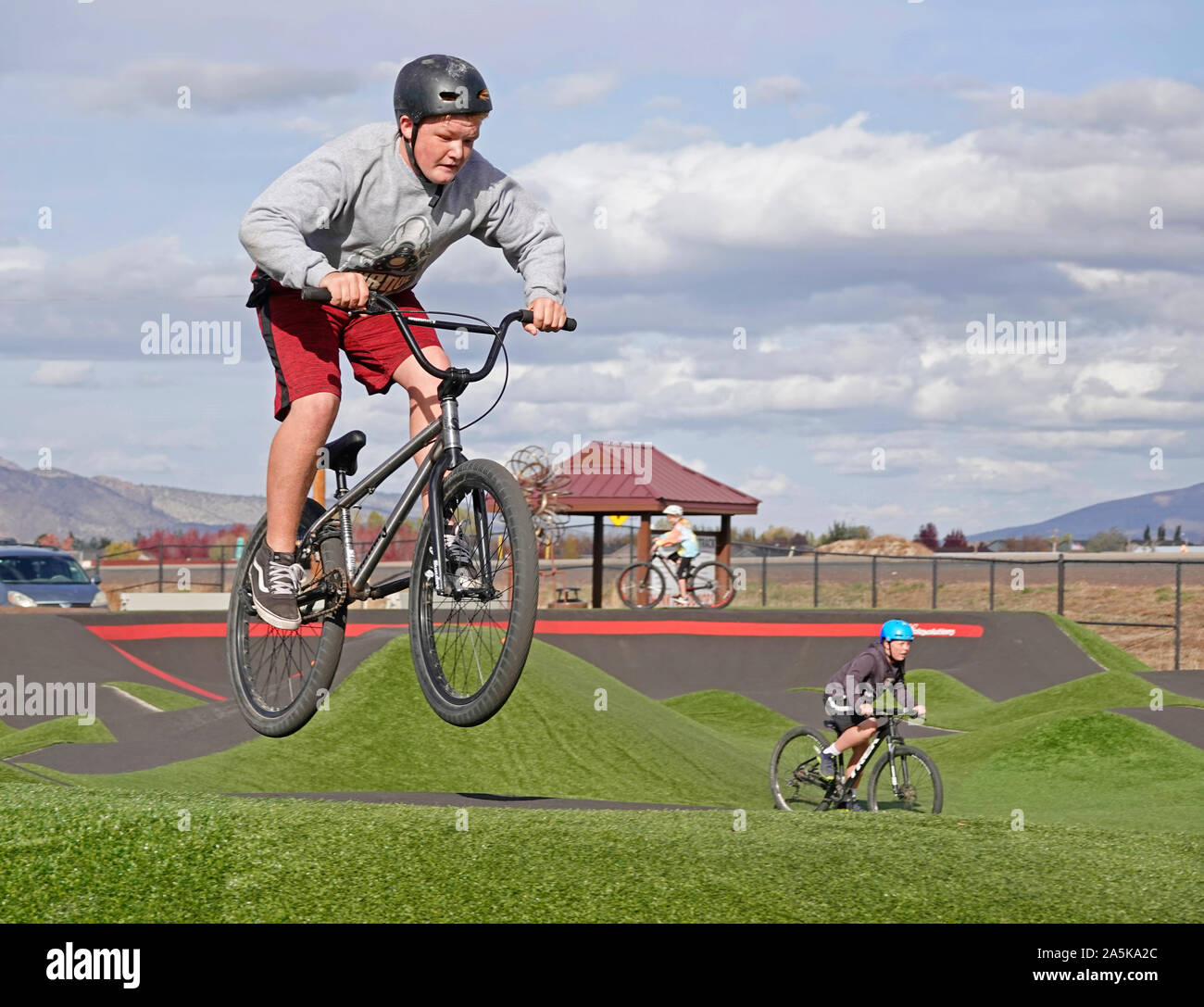 Young bikers navigate their vehicles on a track at a bicycle and skateboard park in Redmond, Oregon Stock Photo