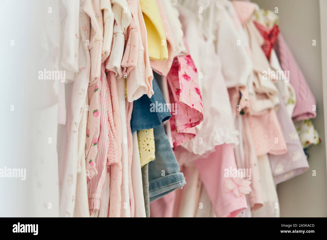 Assortment of baby clothing hung inside cupboard Stock Photo