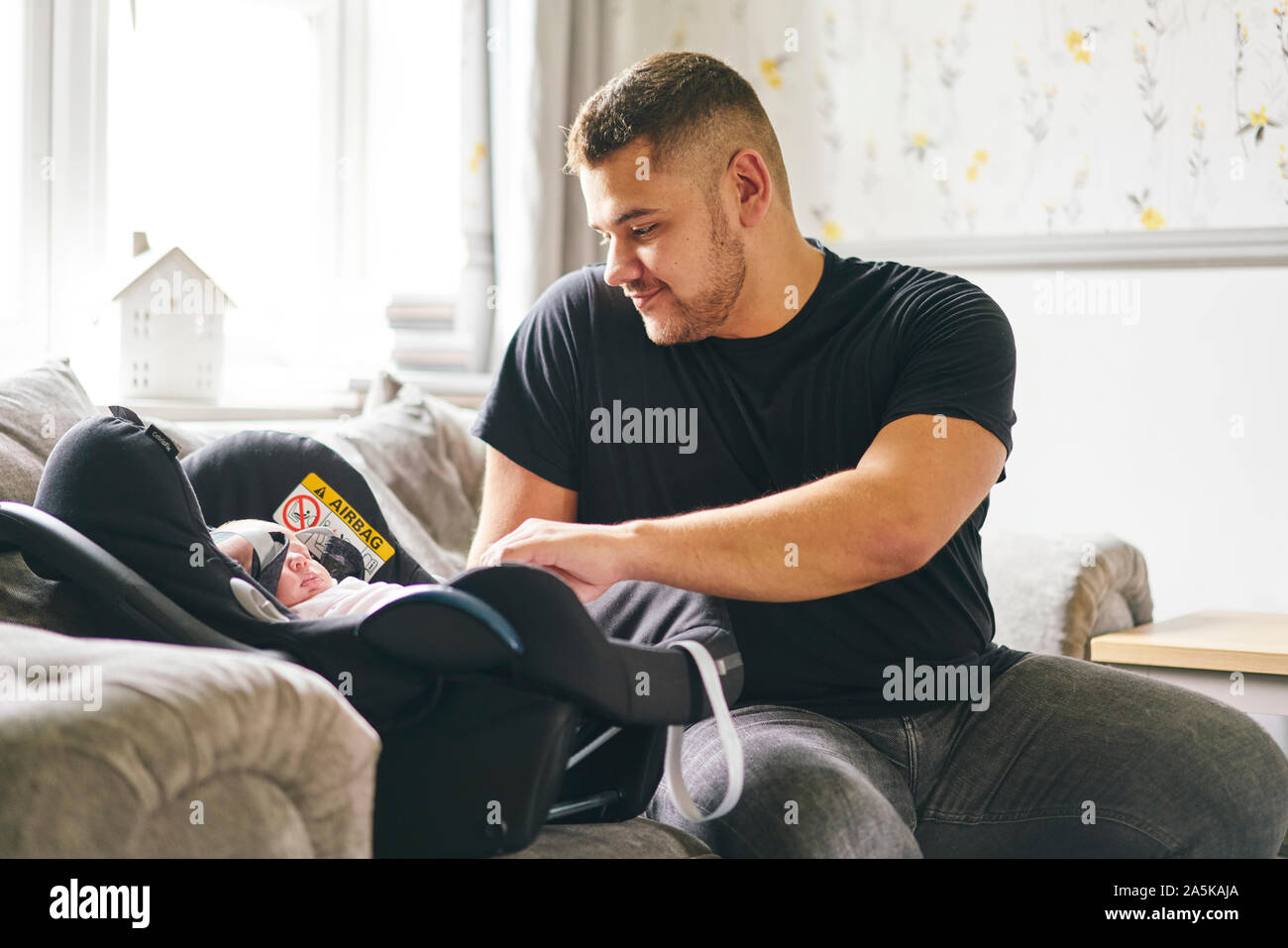 Father buckling up baby in baby cradle Stock Photo