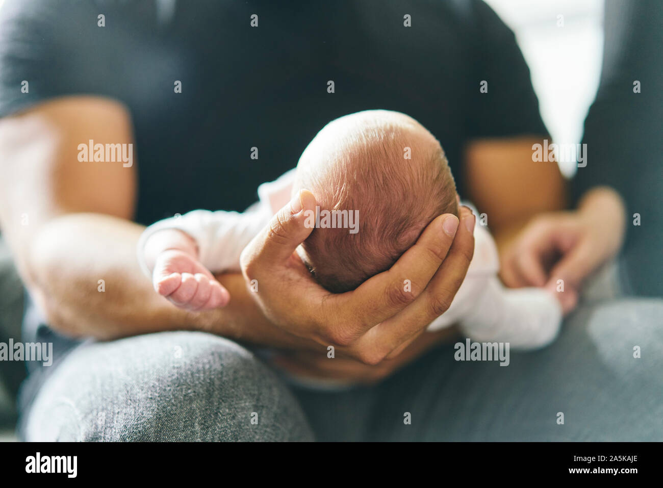 Father supporting head of baby on lap Stock Photo