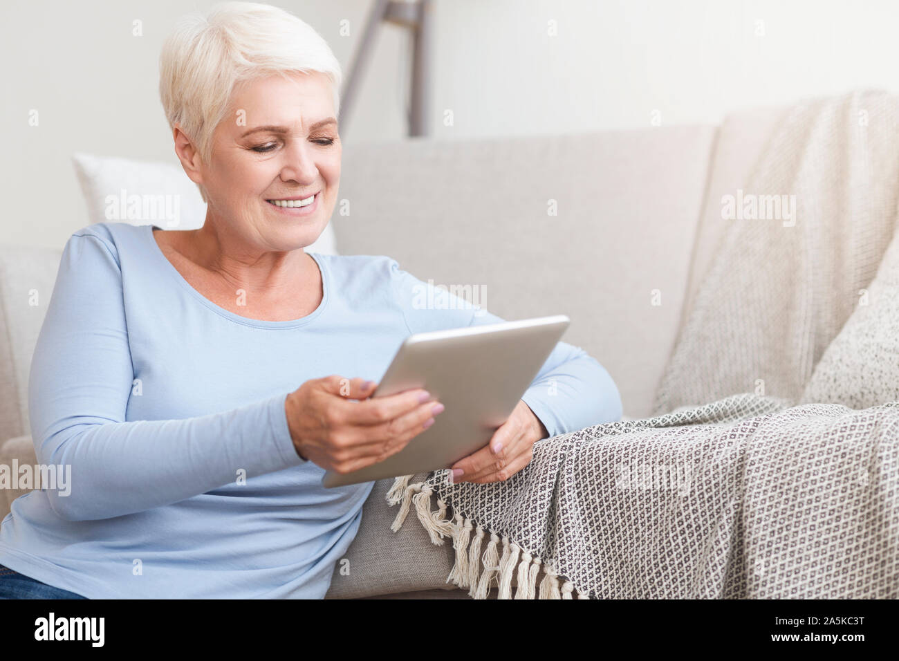 Happy old woman using digital tablet at home Stock Photo