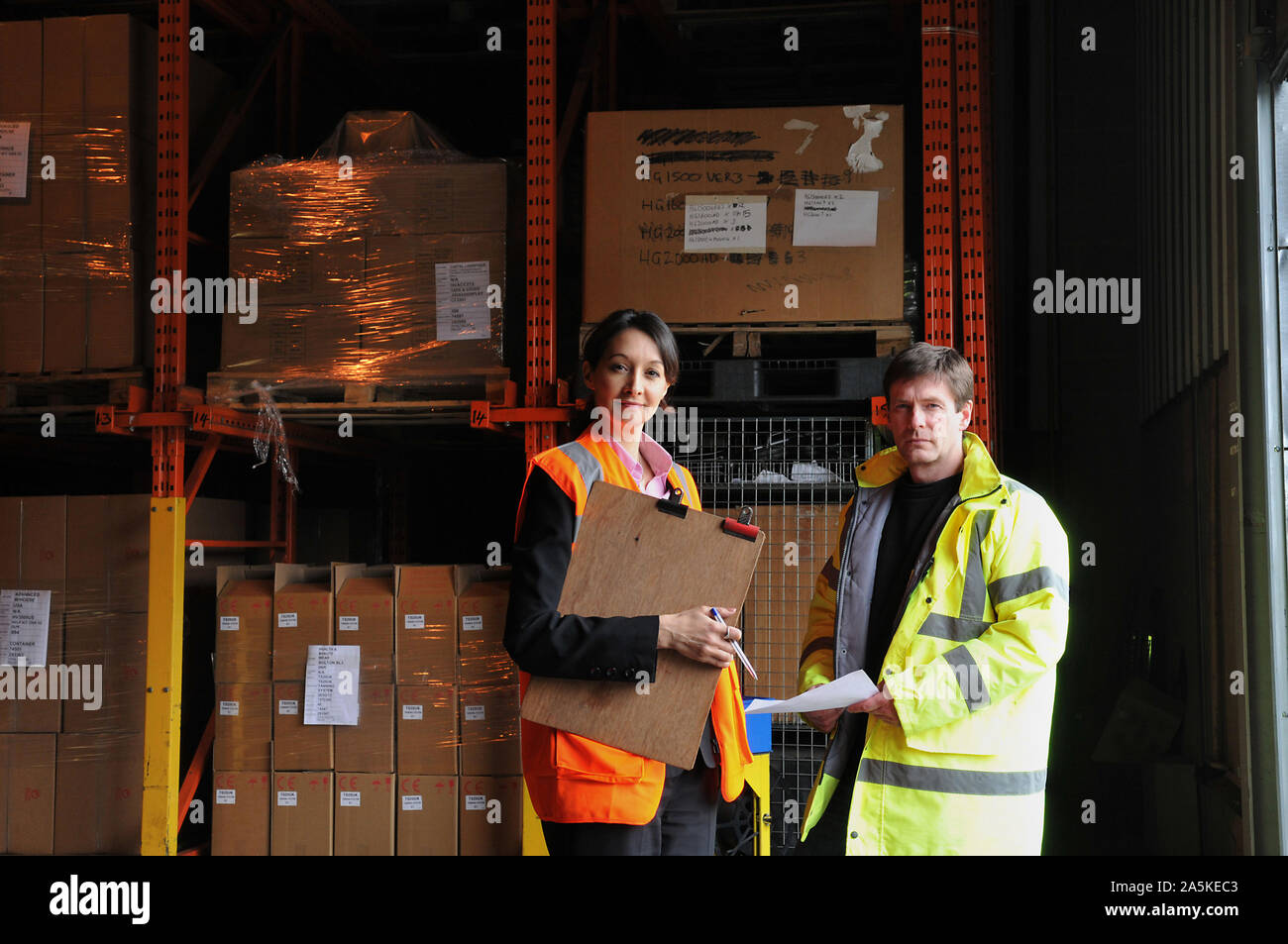 Male and female factory workers with clipboard in warehouse, portrait Stock Photo