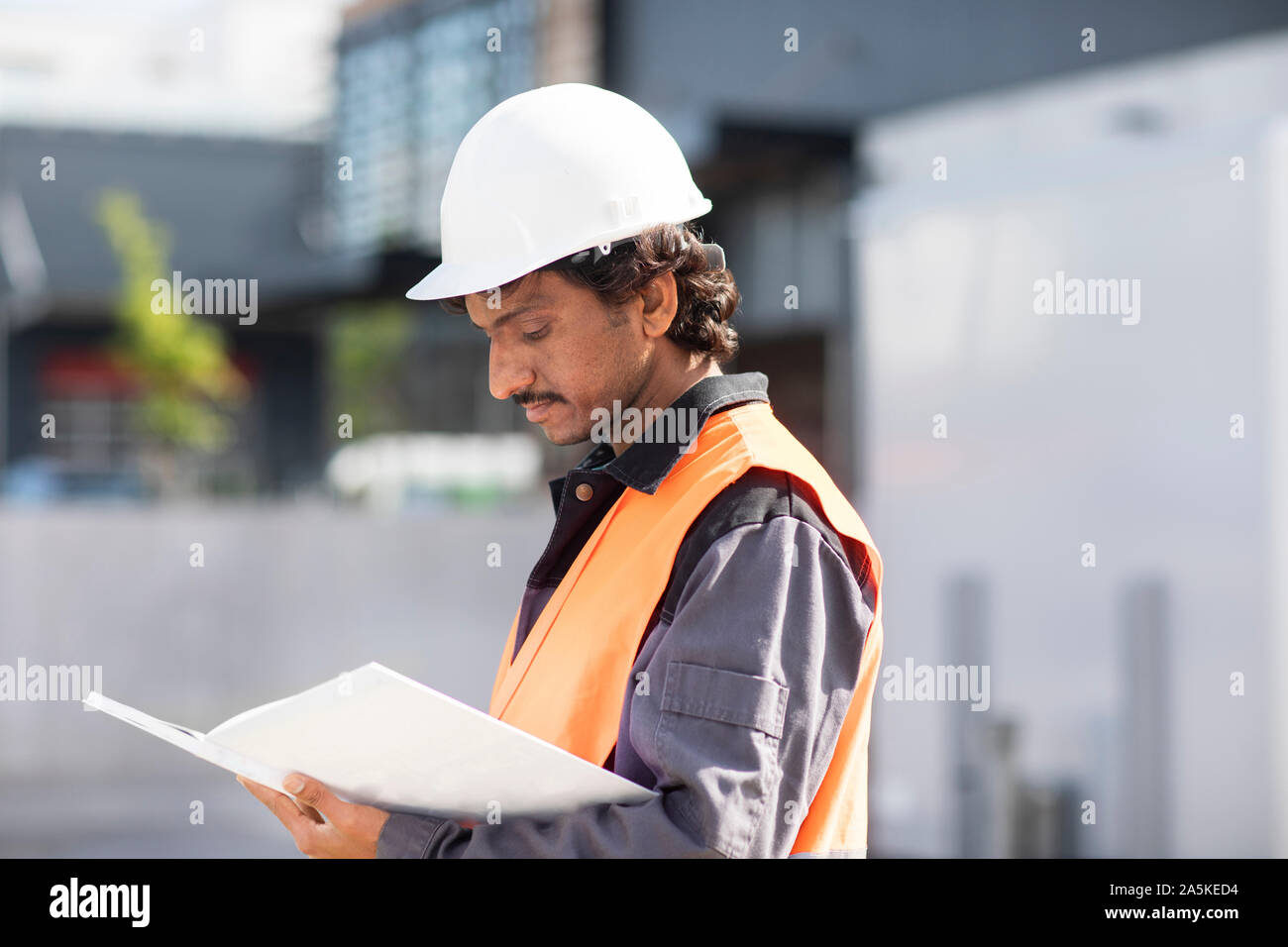 Male engineer looking at plans by industrial building Stock Photo
