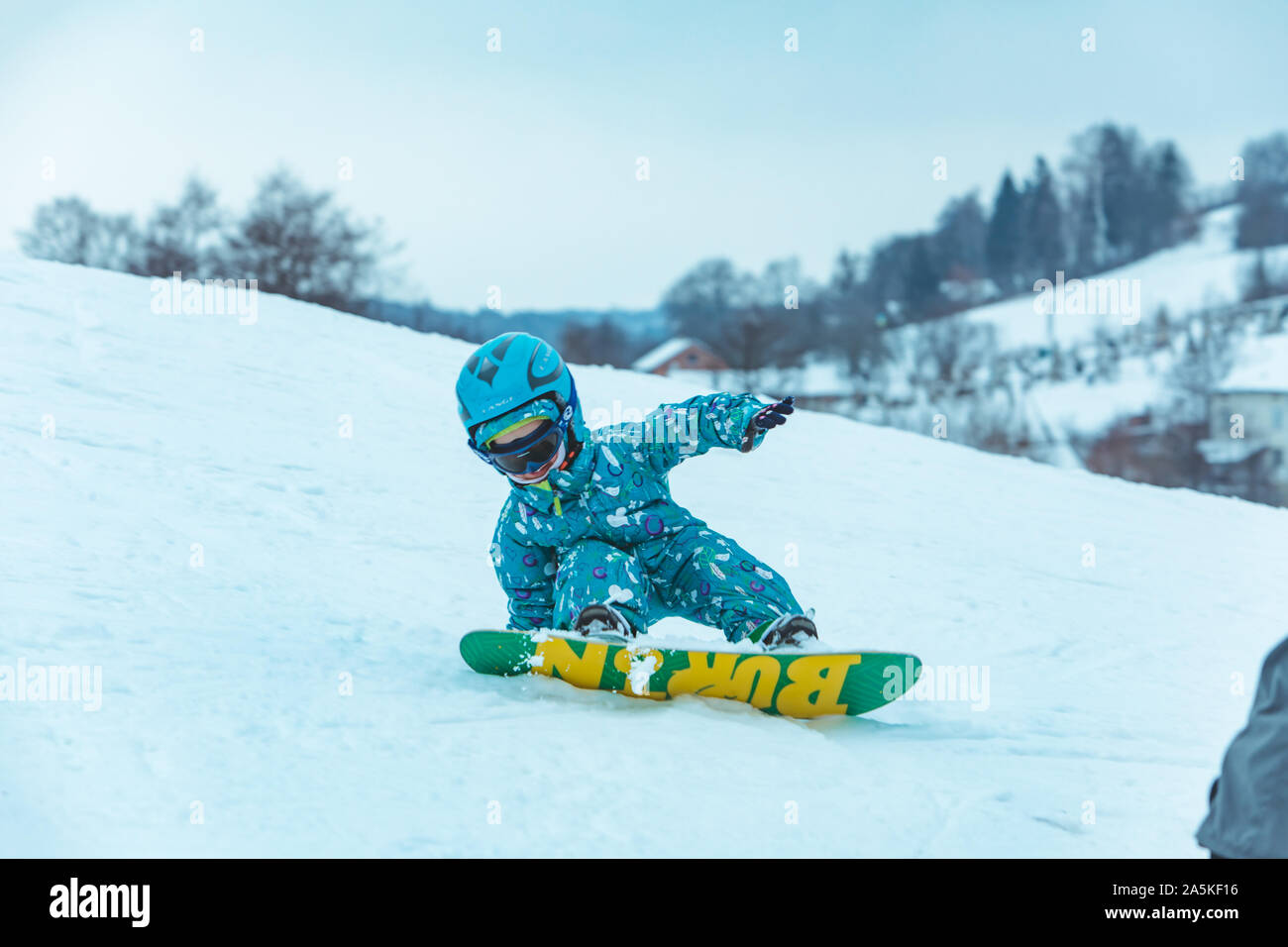 LVIV, UKRAINE - January 12, 2019: little girl learning snowboarding. fall down Stock Photo
