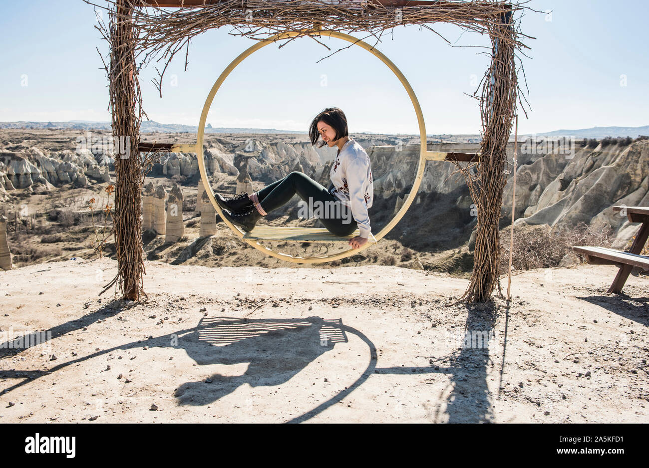 Woman playing on circular swing overlooking fairy chimney valley, Göreme, Cappadocia, Nevsehir, Turkey Stock Photo