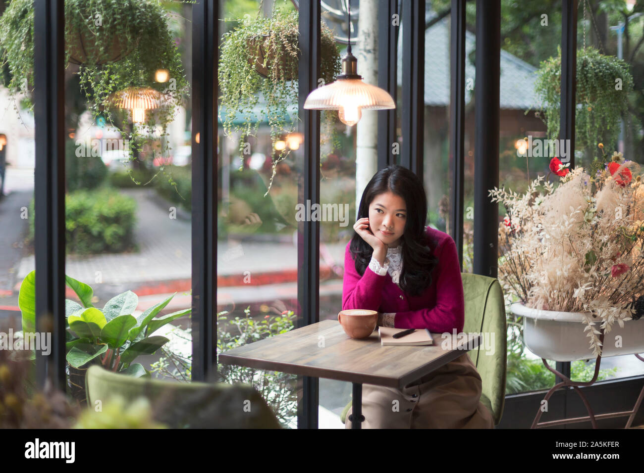 Woman sitting by window in cafe Stock Photo
