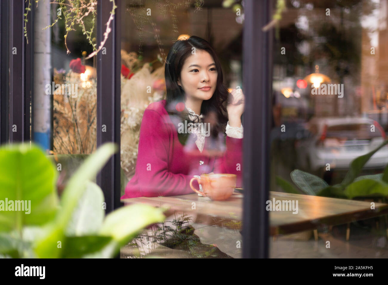 Woman sitting at wooden table in cafe Stock Photo