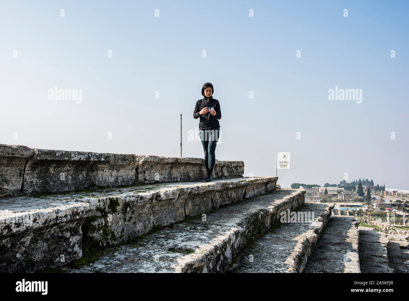 Woman using smartphone on steps, Pamukkale, Denizli, Turkey Stock Photo