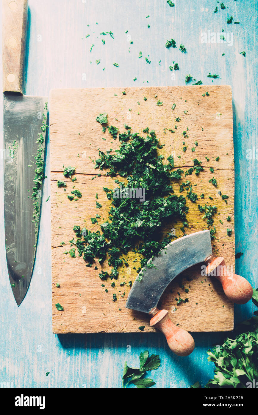 https://c8.alamy.com/comp/2A5KG26/how-to-series-cooking-101-guide-how-to-cut-parsley-top-view-of-fresh-parsley-on-a-cutboard-with-knife-and-mandoline-on-a-rustic-boardflat-lay-comp-2A5KG26.jpg