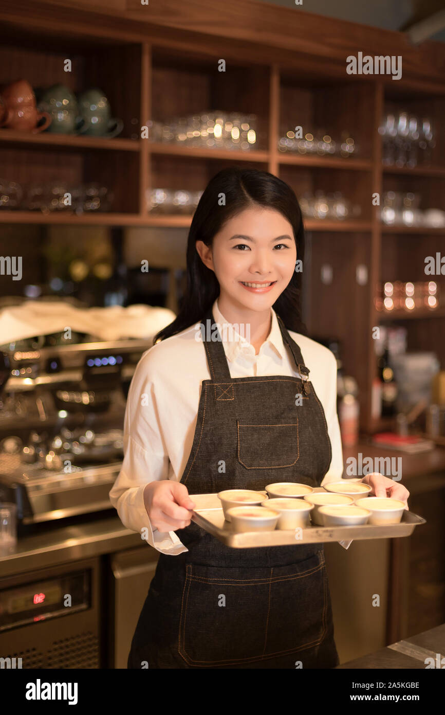 Barmaid standing behind bar counter and holding tray Stock Photo