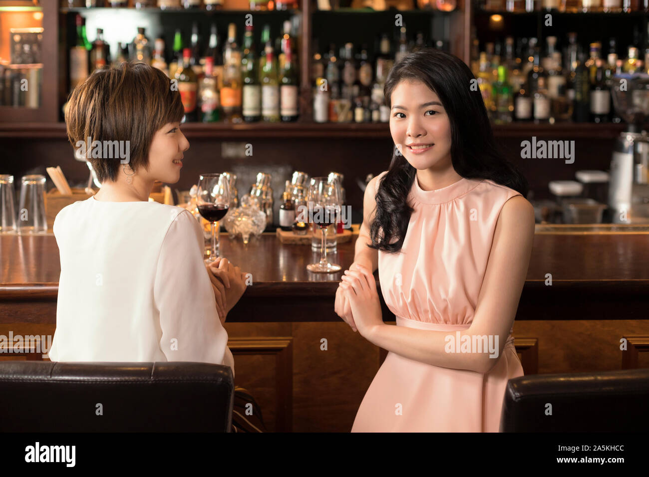 Two smiling young women at bar counter Stock Photo