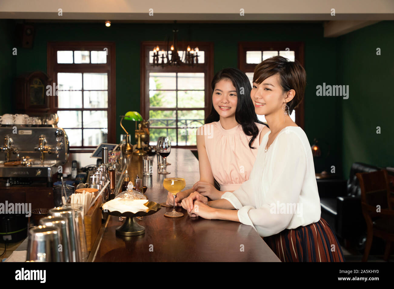 Two smiling young women at bar counter Stock Photo