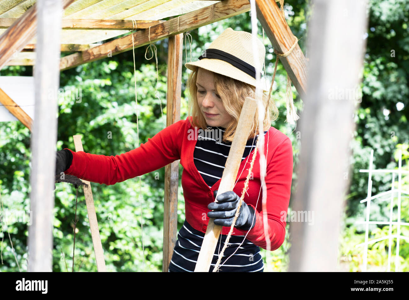 Mid adult woman constructing wooden shelter in her garden Stock Photo