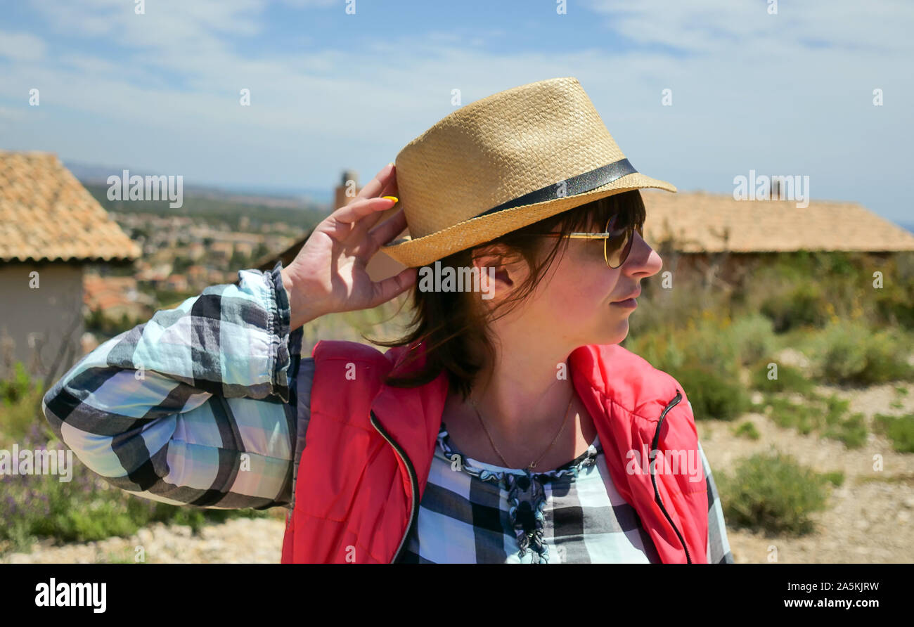 Attractive girl tourist in a hat stands on the street of a small settlement Stock Photo