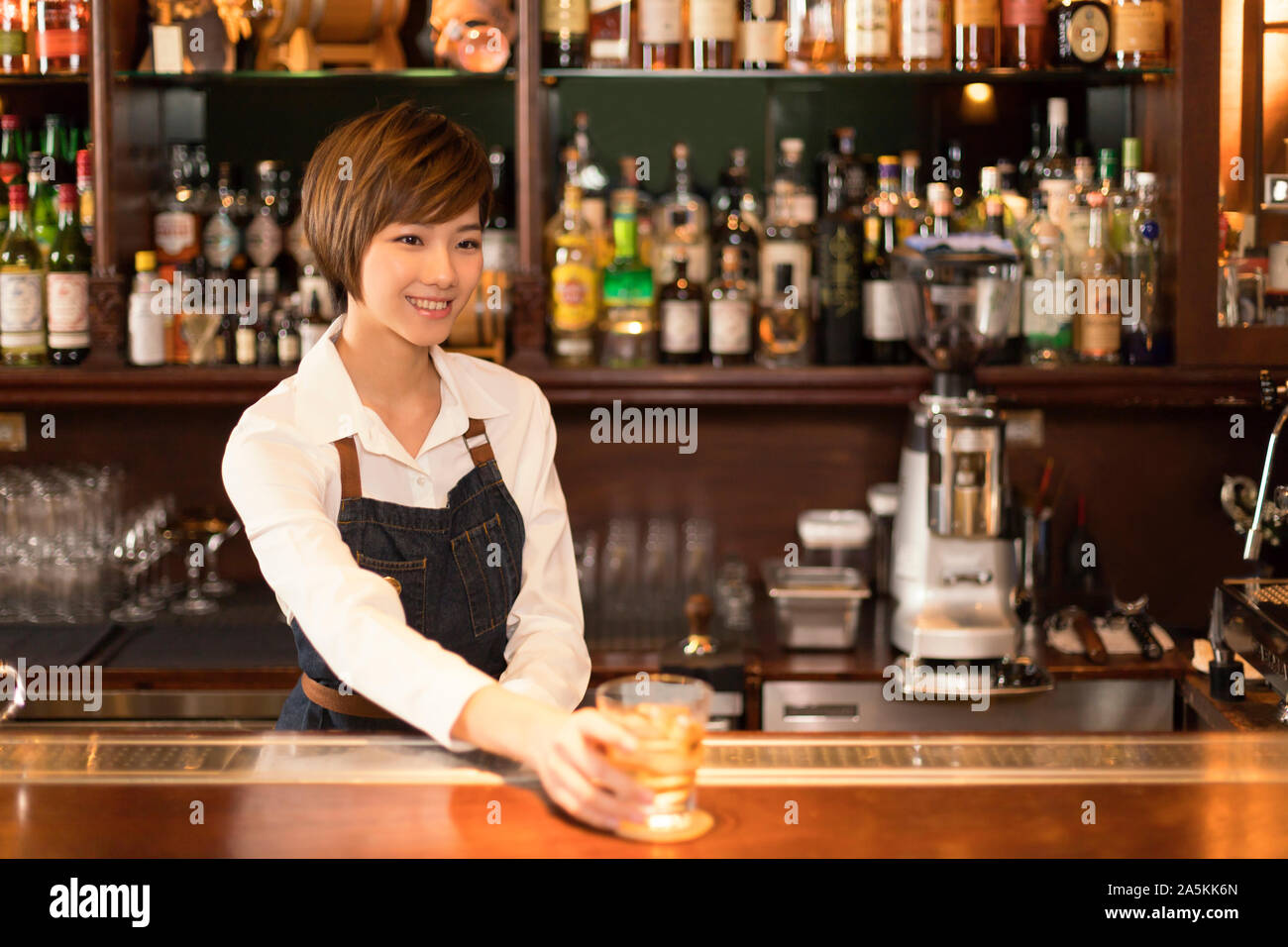 Female bartender serving drink at bar Stock Photo