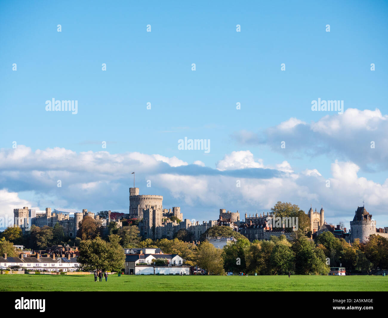 Three People Walking Across The Brocas, Windsor, With Windsor Castle Looming Over Them, Berkshire, England, UK, GB. Stock Photo
