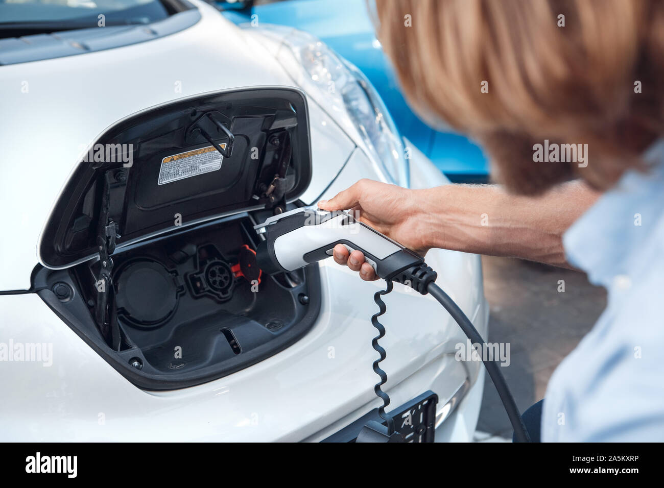 Young adult man holding charging electric car Stock Photo