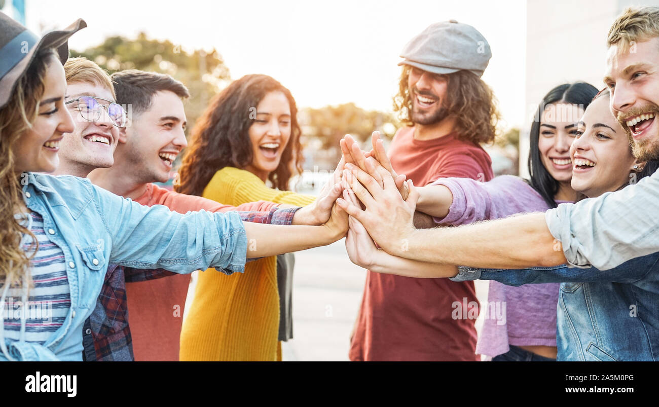 Young friends stacking hands outdoor - Happy millennial people having fun joining and celebrating together Stock Photo