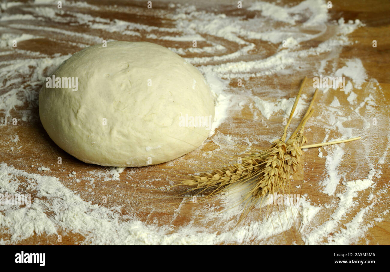 Fresh pasta ready for cooking with wheat ears on a floured wooden table Stock Photo