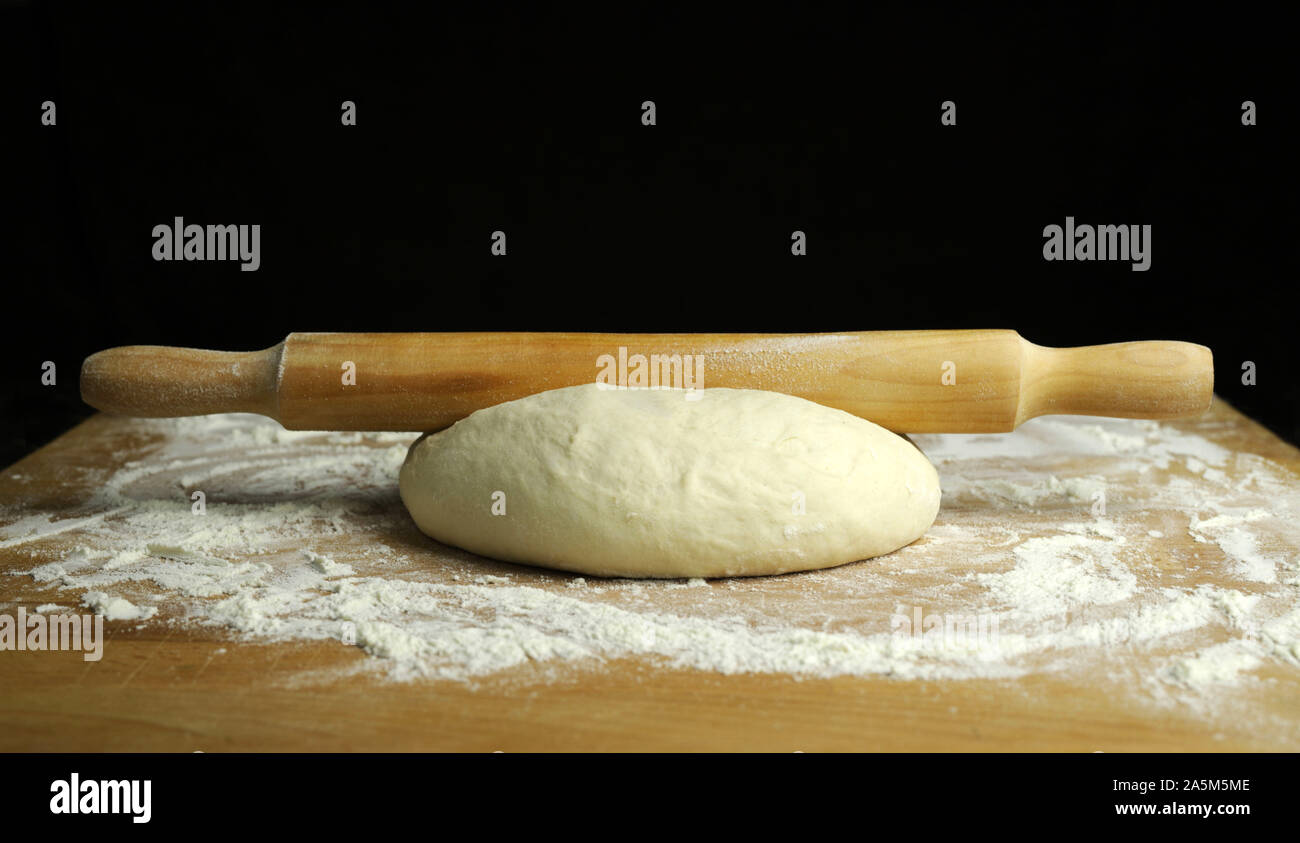 Fresh pasta ready for cooking with a rolling pin on a floured wooden table Stock Photo