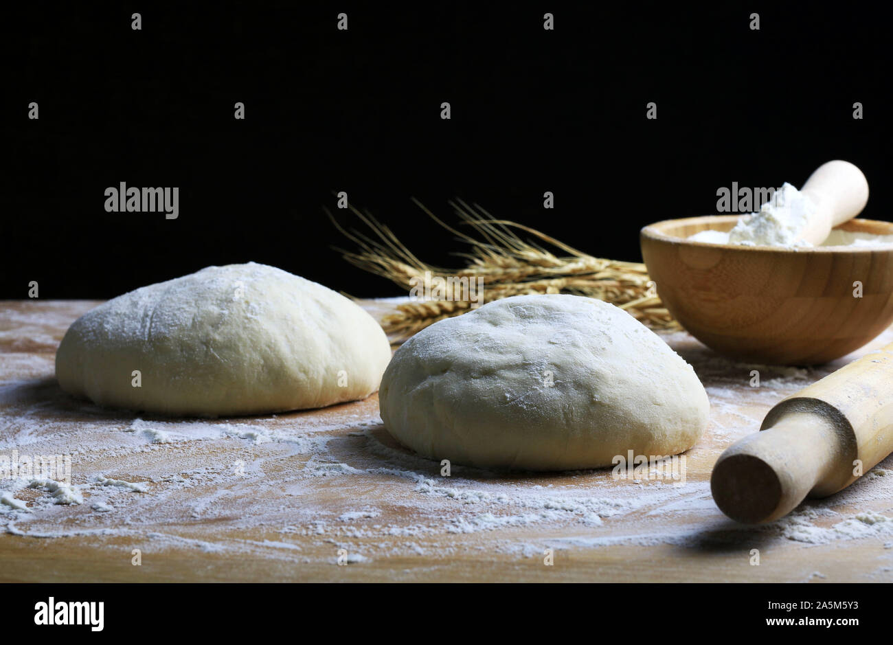 Fresh pasta ready for cooking with wheat ears on a floured wooden table Stock Photo