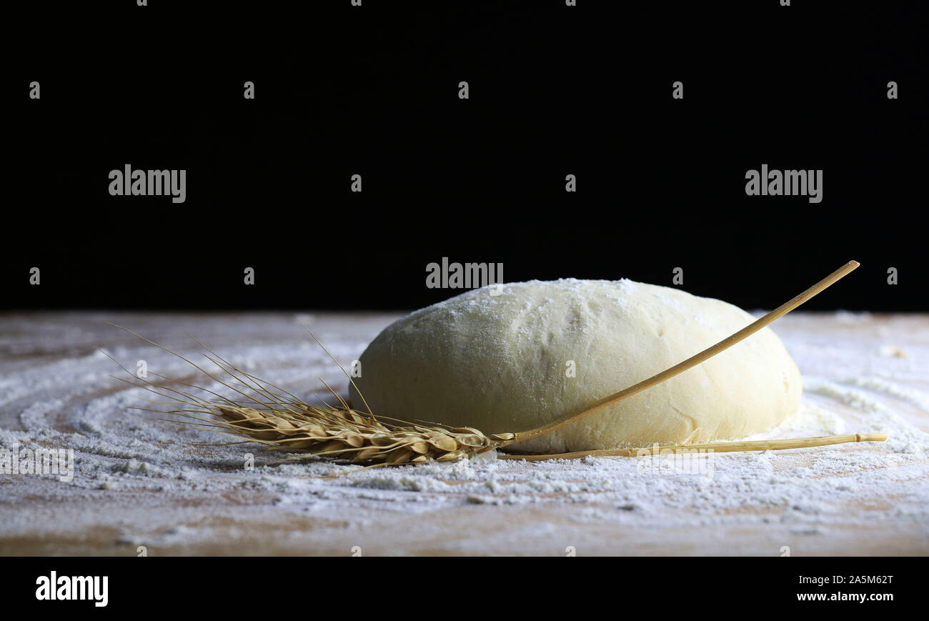 Fresh pasta ready for cooking with wheat ears on a floured wooden table Stock Photo