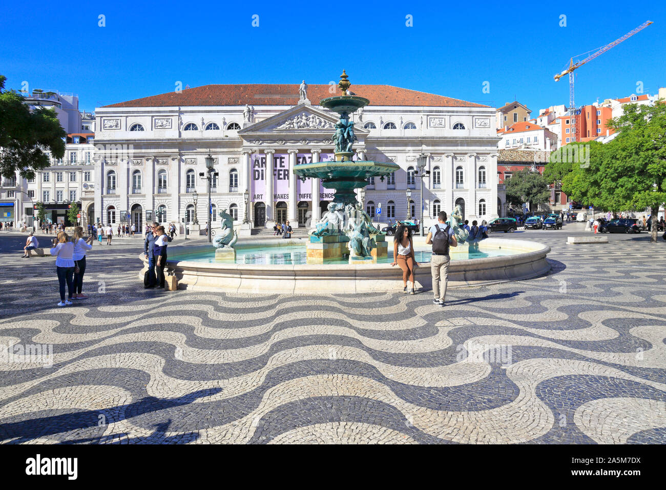 Tourists by the fountain in front of the National Theatre D. Maria II in Rossio Square, Lisbon, Portugal. Stock Photo