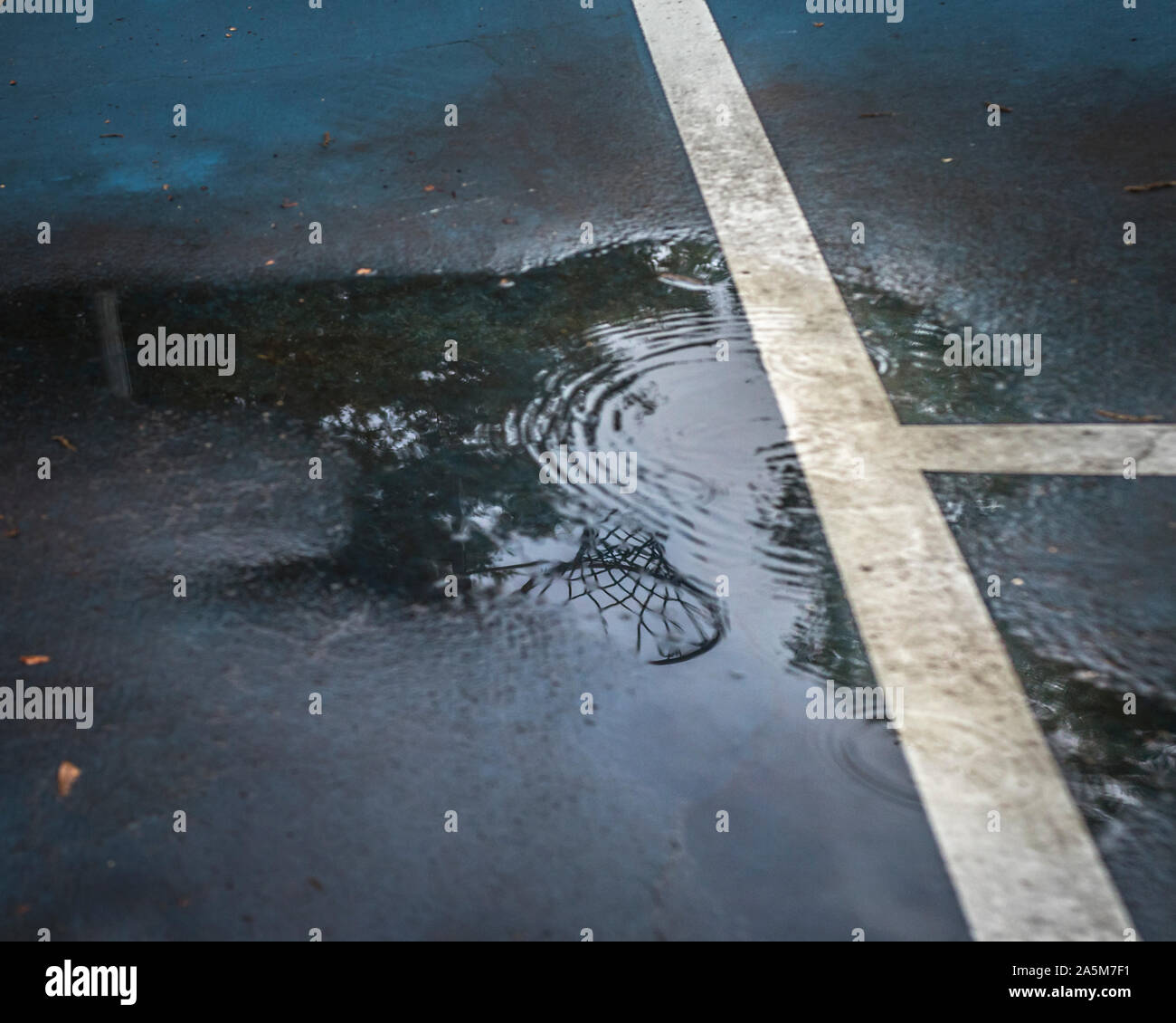 Reflection of basket ball goal in puddle on a rainy day Stock Photo