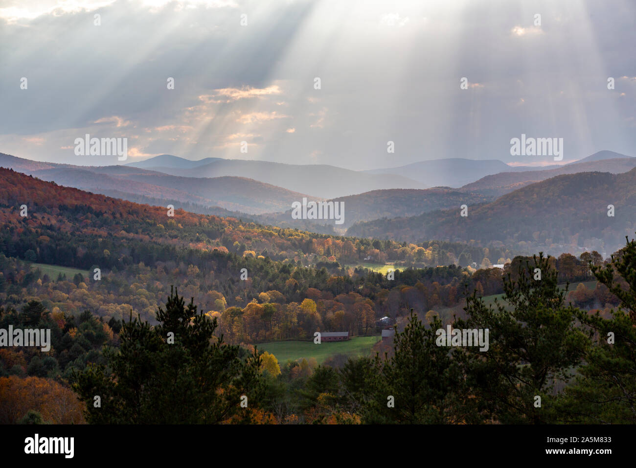 Sunlight beams through clouds above mountains in Quechee, Vermont. Stock Photo