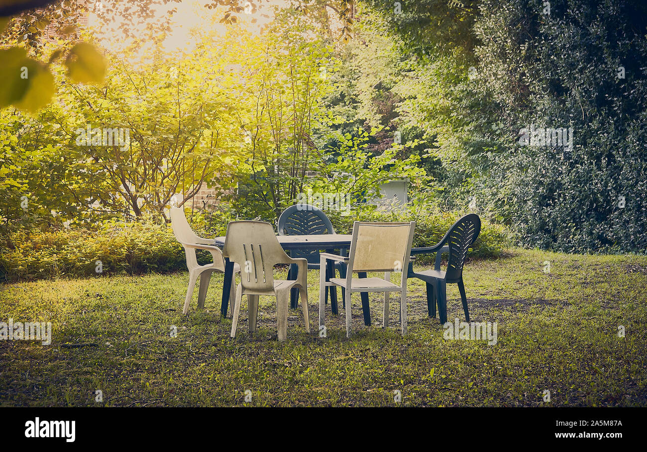 Empty old plastic garden table and chairs on a lawn in woodland Stock Photo
