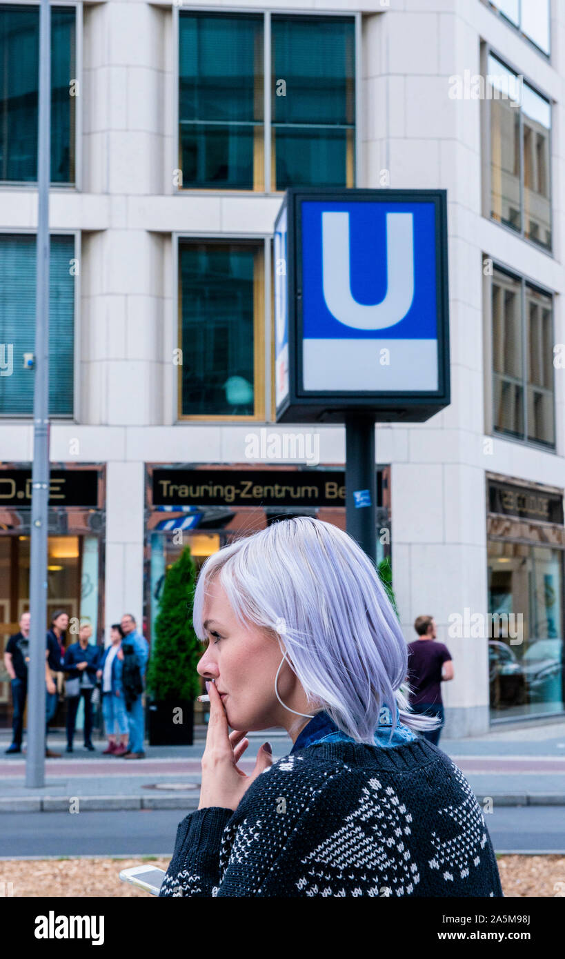 Woman with coloured hair smoking near underground station, Berlin, Germany Stock Photo