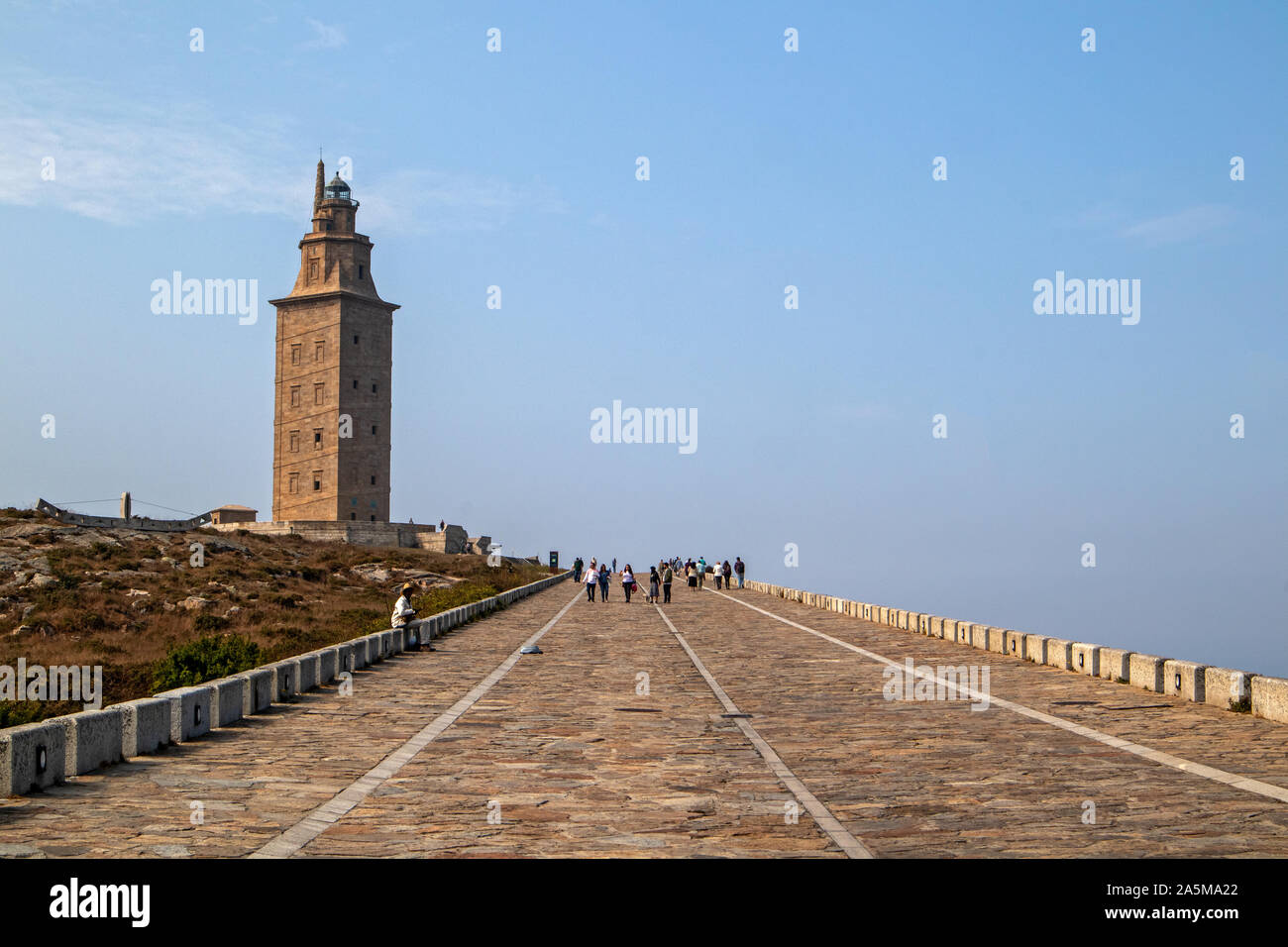 A Coruña, Spain - September 20, 2019: Ancient Roman lighthouse Tower of Hercules (Torre de Hércules) with a bright sky and with tourists visiting it Stock Photo