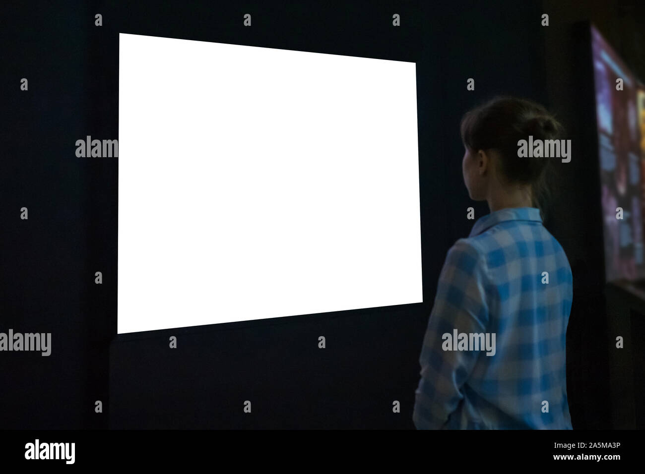 Woman looking at white empty large wall display - mockup image Stock Photo