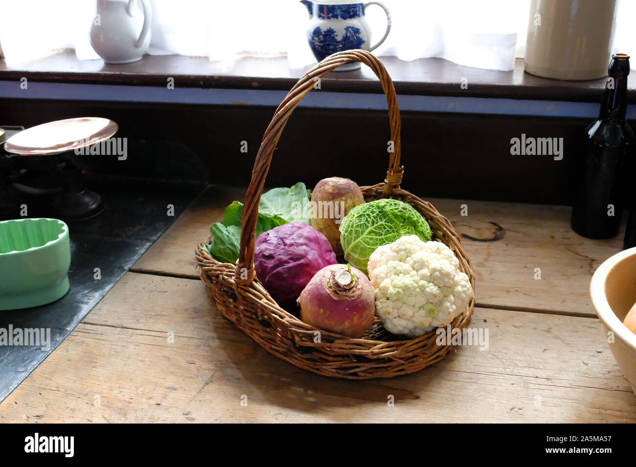 Freshly picked vegetables in a wicker basket lying in front of a window - John Gollop Stock Photo