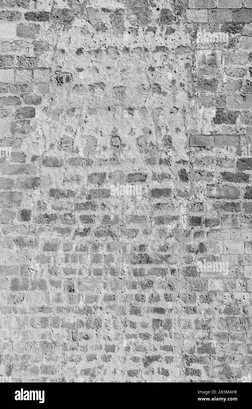 Old and aged brick wall with some weathered plastering. High resolution full frame textured background in black and white. Stock Photo