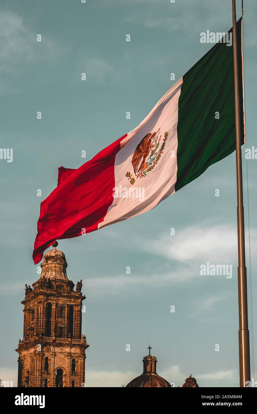 Great Mexican flag waves proudly on Zócalo square, México City. With the Metropolitan Cathedral as Backdrop. Stock Photo