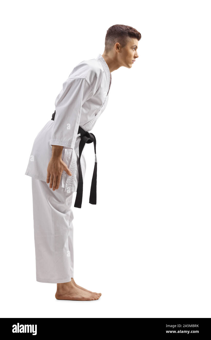 Full length profile shot of young guy in karate kimono with black belt bowing isolated on white background Stock Photo