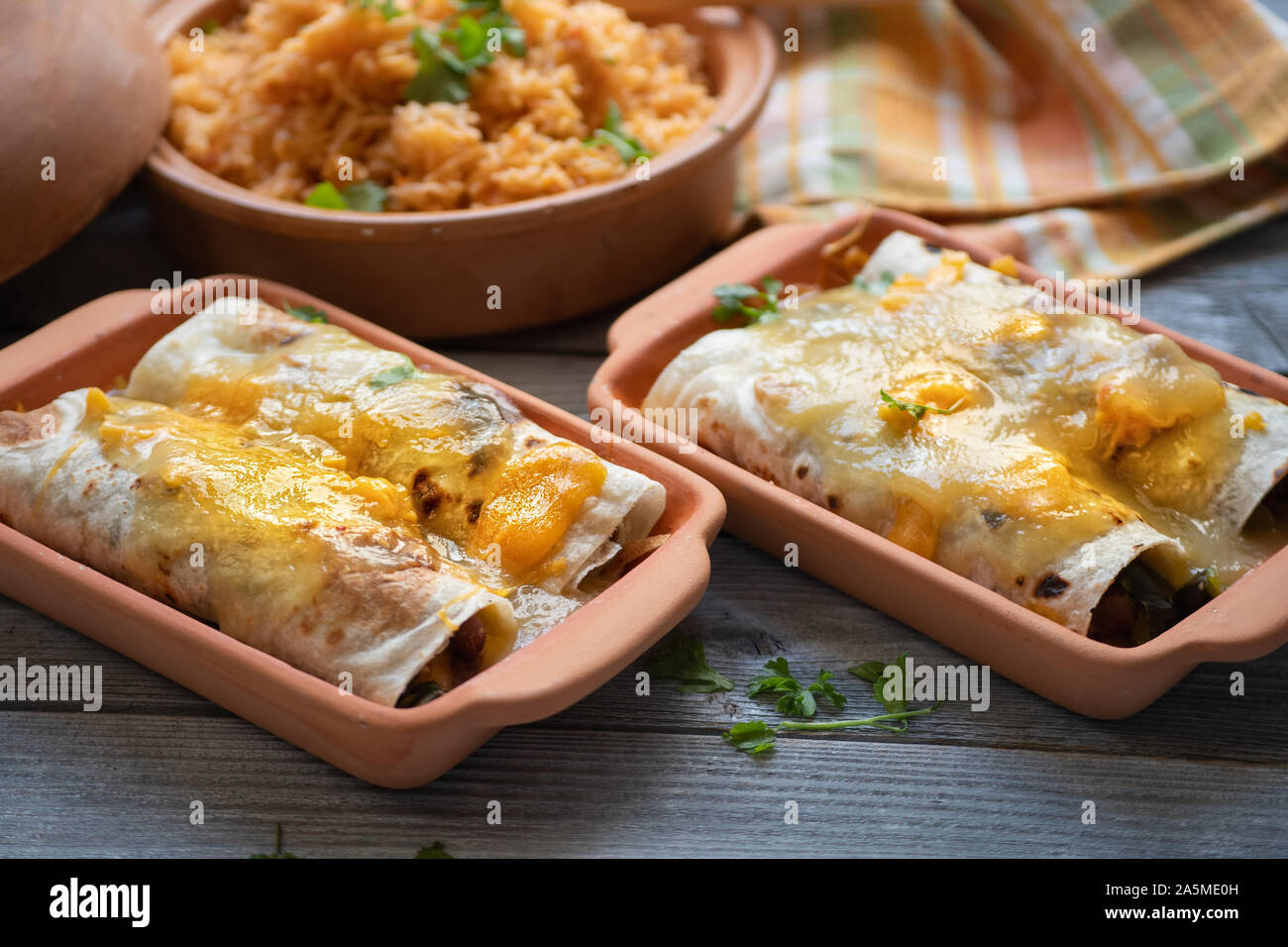 Vegetarian enchiladas with green chile sauce served in clay dishes