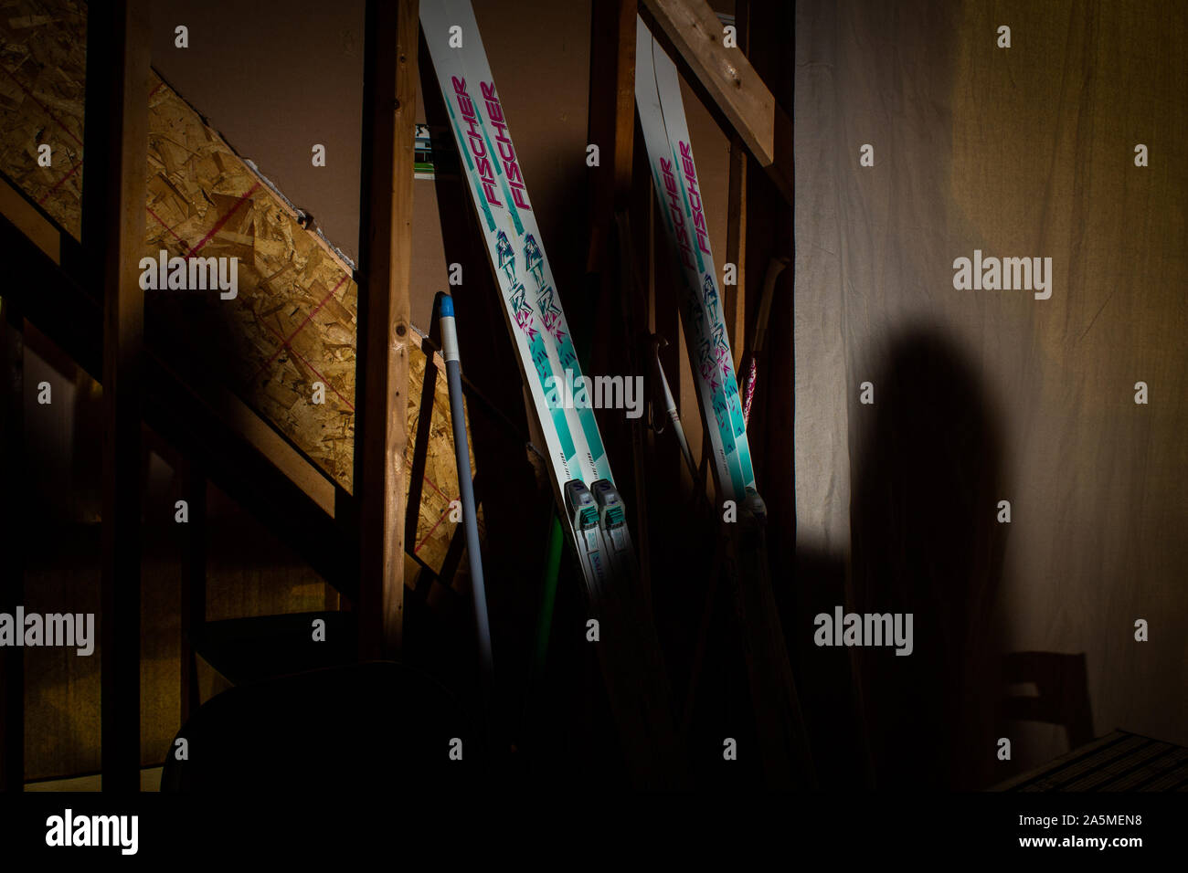 A pair of skis set against a wall and the shadows of three mysterious heads cast against them. Stock Photo