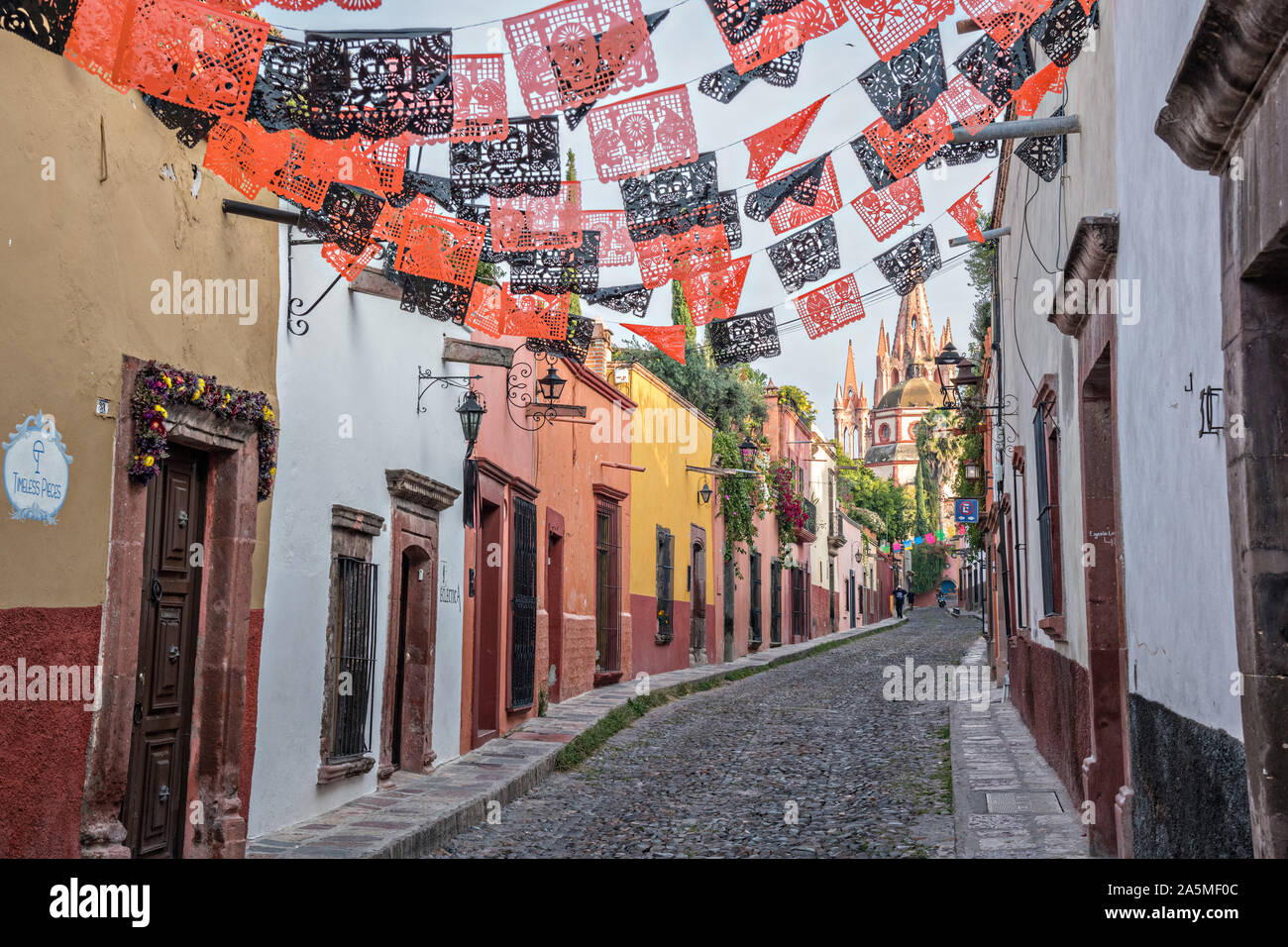 Domes and spires of the Parroquia San Miguel Arcangel church seen through paper banners called papel picado strung to celebrate the Day of the Dead festival on Aldama Street in the historic district of San Miguel de Allende, Mexico. Stock Photo